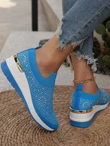 Vista laterale delle sneakers platform blu acceso con strass su tappeto di paglia