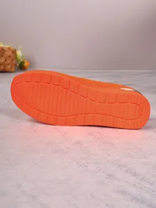 Close-up view of the bright orange slip-resistant sole of a women flyknit sneaker