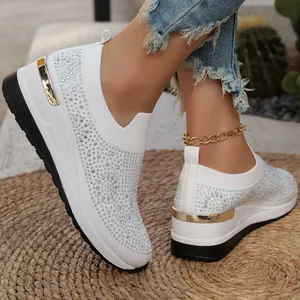 Primo piano di sneakers con zeppa bianche impreziosite da strass e dettagli dorati.