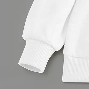 Macro view of elastic ribbed cuff and leaf jacquard pattern on white heavy sweatshirt