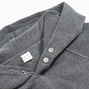 Close-up detail of grey fleece hoodie neckline featuring snap buttons and size label