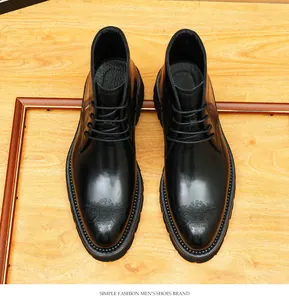 Vista superior de botas de cuero negro para hombre con patrones brogue sobre fondo de madera