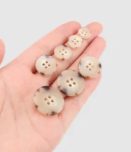 Premium mottled urea garment buttons in various sizes for workwear, held in hand