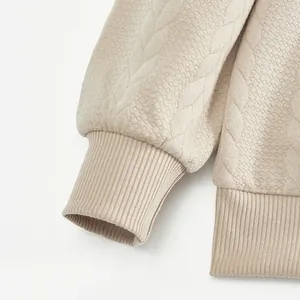 Detailed macro view of textured jacquard and ribbed cuffs on cream sweatshirt
