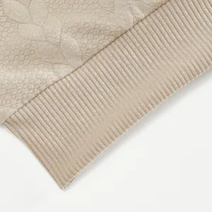 Close-up of beige heavyweight sweatshirt featuring jacquard knit texture and ribbed cuff detail
