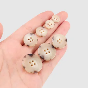 High-end urea resin buttons with tortoise pattern held in hand for size comparison