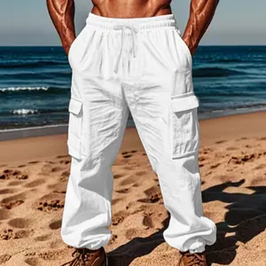 Men's loose fit white cotton linen cargo pants with drawstring and multi-pockets on a beach.