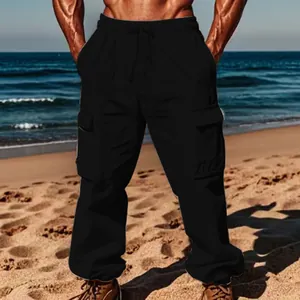 Full view of men's black cargo pants on a model against a sunny tropical beach background.