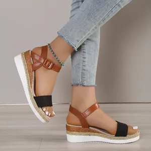 Detail of women's platform wedge sandals with brown buckle straps and black bands.