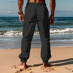 Rear view of black men's casual cargo pants with drawstring waist on beach