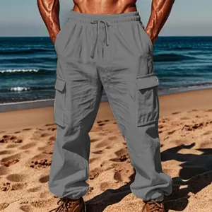 Detailed view of men's loose cargo pants with drawstring and multi-pockets on beach.