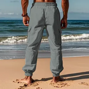 Rear view of grey cotton linen men's cargo pants shown in a sunny outdoor beach setting