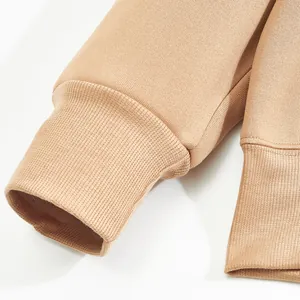 Close-up detail of ribbed cuffs and hem on a camel-colored men's fleece hoodie.