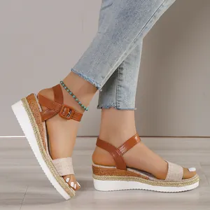 Close-up of stylish brown platform wedge sandals with linen ankle straps on model.