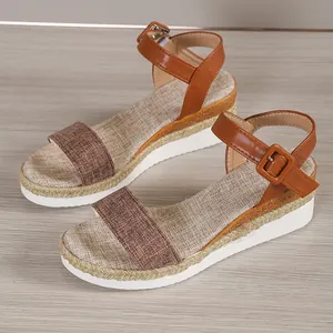 Close-up detail of women's wedge sandals with woven straps and buckle in brown