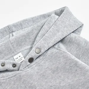 Close-up of grey fleece hoodie neckline featuring metal snap buttons and size tag