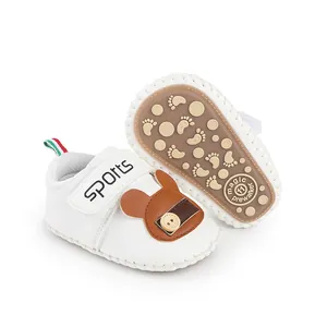 Dettaglio di scarpine primi passi bianche per neonato con decoro orsetto e suole antiscivolo