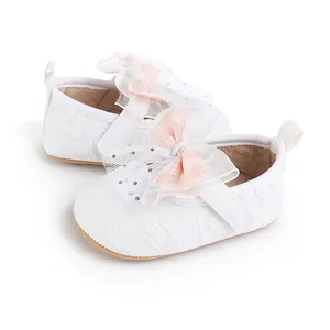 Detailed close-up of white baby walker shoes with decorative pink mesh bow and soft sole
