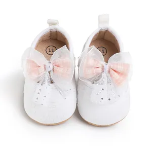 Close-up of white baby pre-walker shoes with large pink lace bows and floral pattern