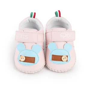 Dettaglio di scarpine primi passi rosa per neonati con patch animale blu e velcro