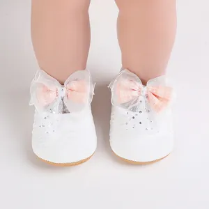 Close-up view of white infant walking shoes featuring decorative lace and peach plaid bows