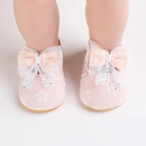 Detailed close-up view of pink baby pre-walker shoes featuring a large lace bow and floral pattern