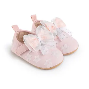 Detailed view of pink baby walking shoes with lace bow and floral embroidery