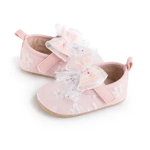 Close-up of pink baby pre-walker shoes with elegant white lace bows and floral patterns