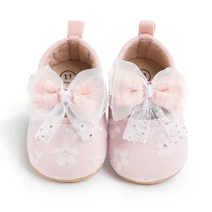 Close-up view of pink baby pre-walker shoes featuring decorative mesh bows and floral patterns.