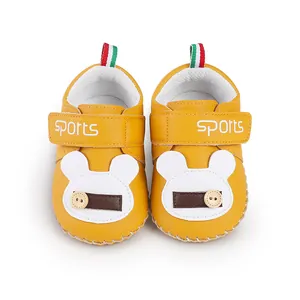 Vista dall'alto di scarpe primi passi gialle per neonati con design orsetto cartoon.