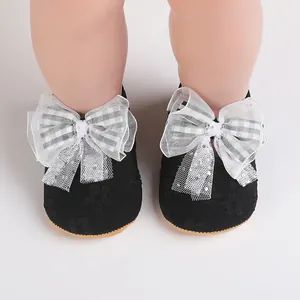 Detail view of black lace baby walking shoes with decorative white plaid bows.