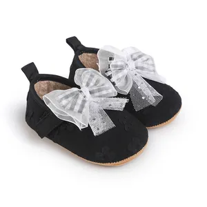 Close-up of black baby walking shoes with large white mesh bows and lace details.