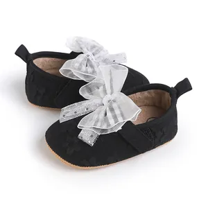Detailed view of black infant walker shoes featuring a delicate white organza bow