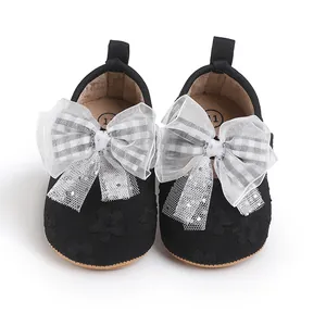 Detailed view of black baby walker shoes featuring a large lace bow and sparkles