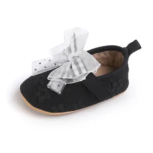 Close-up of black baby walking shoe with a large white tulle bow and floral texture.