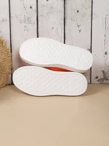 Detailansicht der weißen Plateausohle eines orangefarbenen Damen-Slippers aus Strick