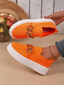 Detailansicht der orangen Strick-Sneaker mit Goldkette und Plateausohle.
