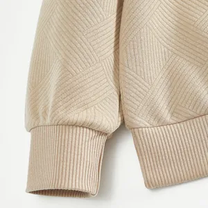 Gros plan sur les poignets côtelés et le tissu jacquard d'un sweat-shirt beige épais