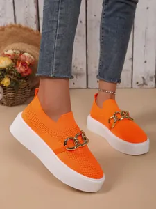 Detailansicht der orangefarbenen Flyknit-Sneaker für Damen mit dicker weißer Sohle und Kette