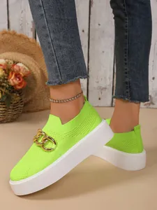 Nahaufnahme neongrüner Flyknit-Sneaker mit Goldkette und weißer Plateausohle