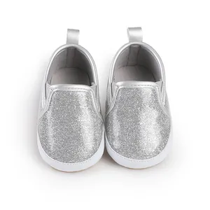 Nahaufnahme von glänzenden silbernen Glitzer-Lauflernschuhen für Babys mit weichen Sohlen
