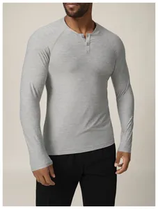 Vue détaillée d'un t-shirt de sport gris à manches longues et col Henley sur un modèle.