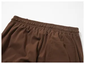 Detailaufnahme des elastischen Bunds und der Gesäßtasche der braunen Herren-Jogginghose.