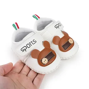 Primo piano di scarpe bianche per neonati con disegno di orso e chiusura a strappo
