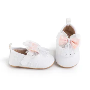 Close-up of white infant walking shoes with pink lace bow and hook-and-loop strap