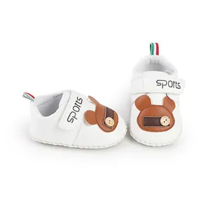 Dettaglio scarpe primi passi bianche per neonato con toppa a orsetto e chiusura a strappo