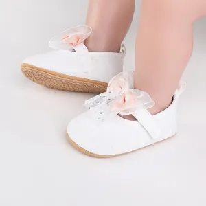 Detailed view of white baby walking shoes with a delicate tulle bow and non-slip sole.