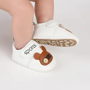 Primo piano di scarpine bianche per neonati con patch orso sui piedi
