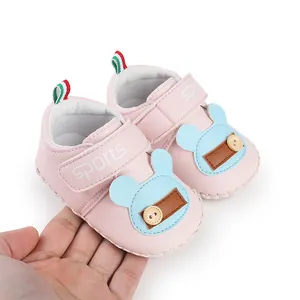 Dettaglio scarpine neonato rosa con decorazione orsetto blu e chiusura velcro