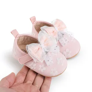 Close-up of pink baby walker shoes with decorative white mesh bows and flower embroidery
